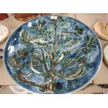 A large studio pottery charger by Poole having deep blue green hues with imagery of birds in tree