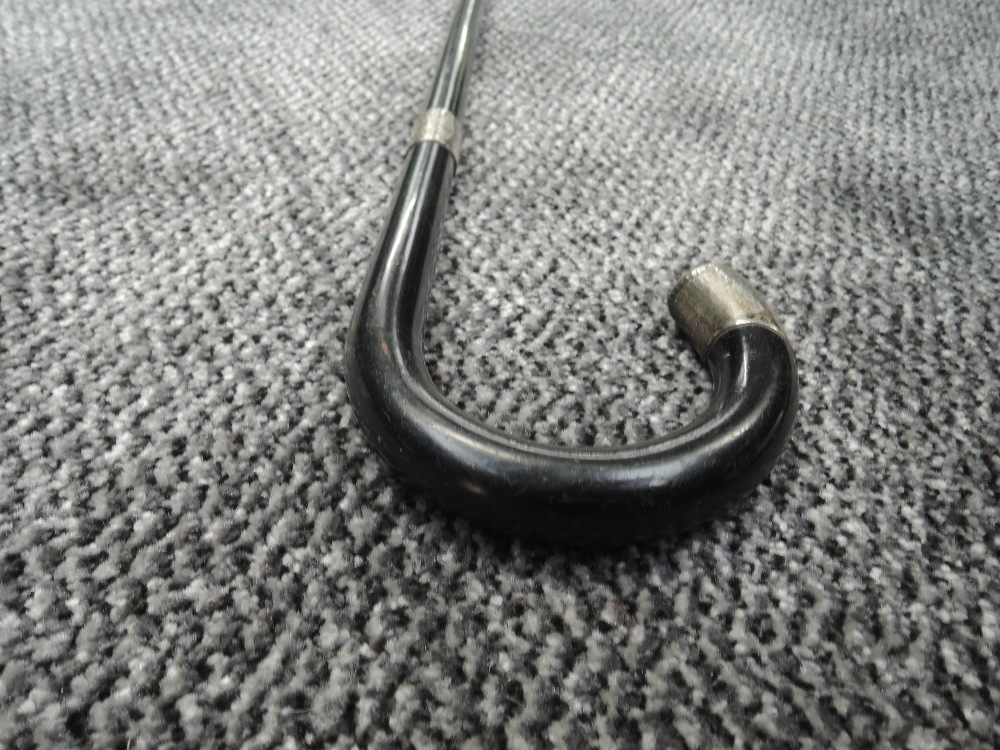 An ebonised walking stick having HM silver ferrule and tip