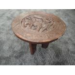 A traditional ethnic wood carved folding table of African design standing 38cm tall