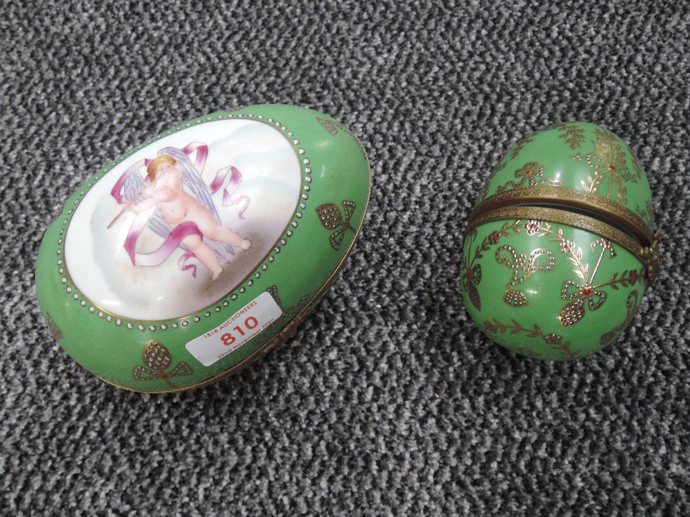 Two ceramic Russian style eggs having cherub decoration with green ground and gold detailing