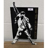 A Freddie Mercury commemorative stand, made from hard plastic, 34cm by 20cm wide.