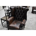 A traditional brown leather wing back armchair