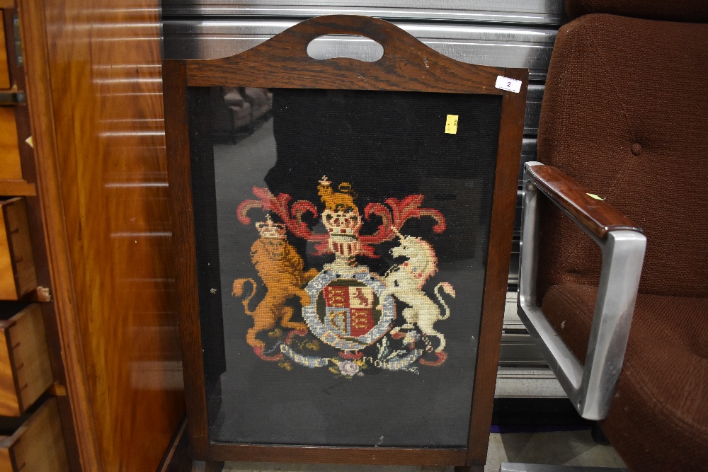 An early 20th Century fire screen having woolwork coat of arms inset