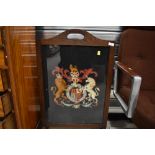 An early 20th Century fire screen having woolwork coat of arms inset