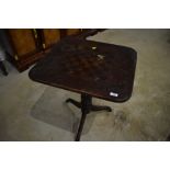 A 19yh Century stained frame pedestal occasional table, with faded chequer board top, some