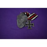 A German WW1 Iron Cross dated 1813-1914 and a German WW2 Demjansk 1942 Shield, bearing cross