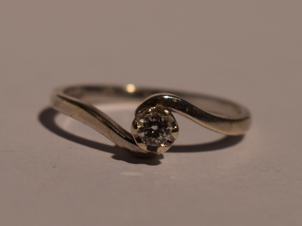 A lady's diamond solitaire dress ring, approx 0.1ct in a raised claw mount to crossover shoulders on