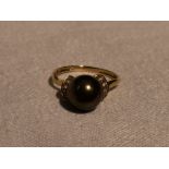 A lady's dress ring having a simulated black pearl flanked by cubic zirconias on a 14ct gold loop,