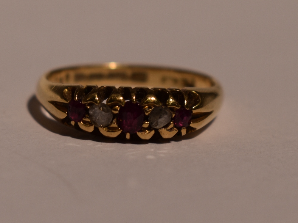 A lady's dress ring having a trio of rubies interspersed by two old cut diamonds in a gallery