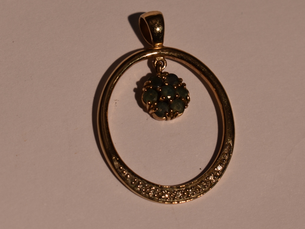 A 9ct gold pendant of loop form having diamond chip decoration and an emerald set cluster drop,