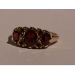A lady's dress ring having a trio of garnets interspersed by garnet chips in a gallery mount on a