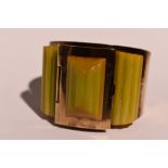 An Art Deco brass and amber style celluloid bangle having a hinged powder compartment to top and a