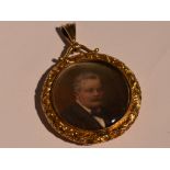 A yellow metal glass locket containing hand painted Edwardian portraits within a decorative