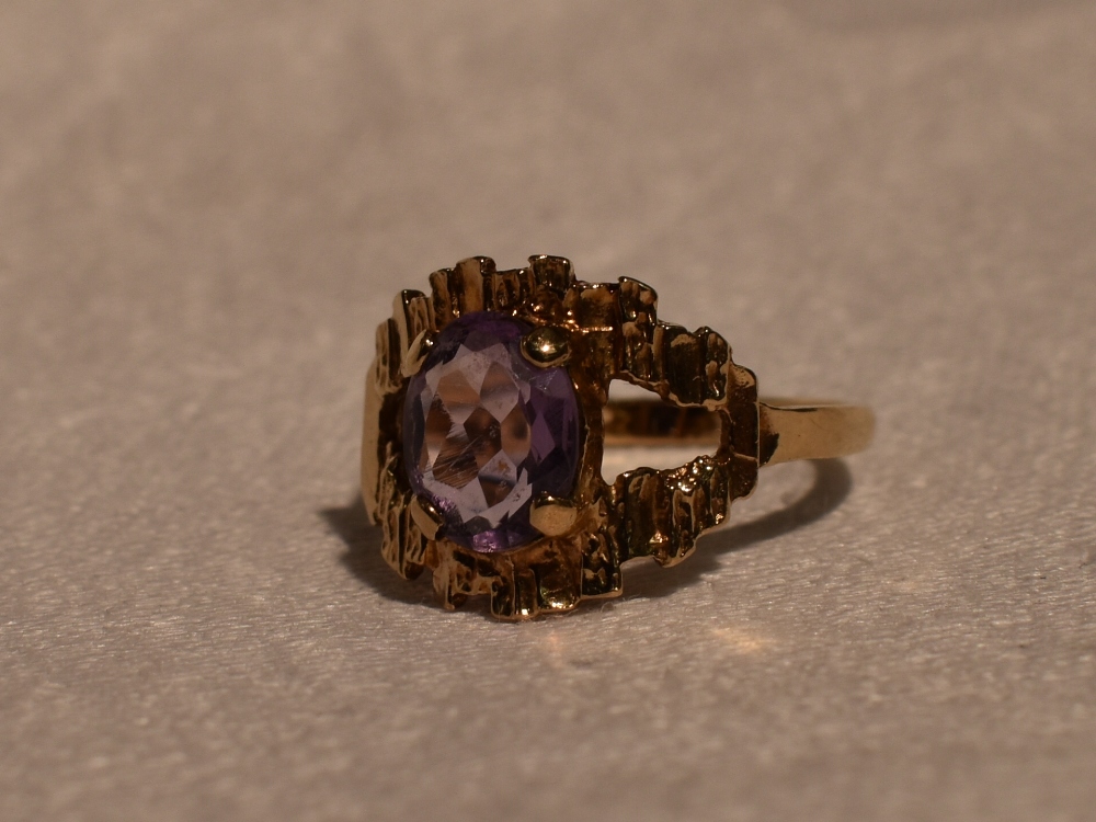 A lady's dress ring having an oval amethyst in a stylised open mount on a 9ct gold loop, size N &