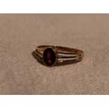 A lady's dress ring having an oval ruby style stone in a collared mount to open triple bar shoulders