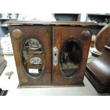 A miniature oak cased jewellery box with internal drawers and beveled glass doors