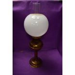 A brass table top oil lamp with spherical milk shade.