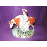 A Staffordshire style figurine depicting milk maid and cow.