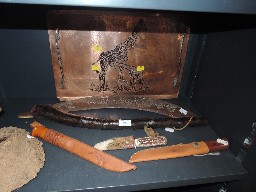 A collection of knives, a copper tray with giraffe decoration, a boomerang and a shillelagh with