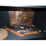 A collection of knives, a copper tray with giraffe decoration, a boomerang and a shillelagh with