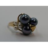 A lady's dress ring having black and white cultured pearls in a yellow metal stylised mount on a