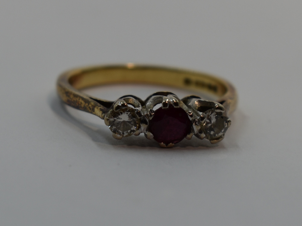 A lady's dress ring having a central ruby flanked by two diamonds, each stone approx 0.128ct in a