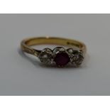 A lady's dress ring having a central ruby flanked by two diamonds, each stone approx 0.128ct in a