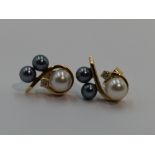 A pair of cultured black and white pearl stud earrings with diamond chip decoration in yellow