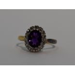 A lady's dress ring having a heat treated oval amethyst and diamond cluster in a stepped claw set