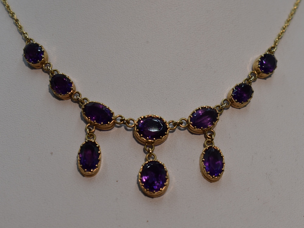 A ten stone heat treated amethyst necklace having seven graduated stones with three drops on a fixed