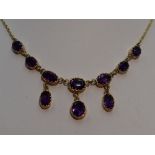 A ten stone heat treated amethyst necklace having seven graduated stones with three drops on a fixed