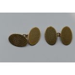 A pair of 9ct gold cufflinks of oval form having engine turned chequered decoration and chain