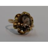 A lady's dress ring having an oval smoky quartz in an open frilled claw set mount on a 9ct gold