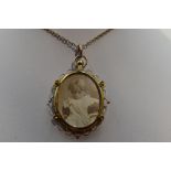 A glass locket of oval form having a decorative 9ct gold mount on a yellow metal chain stamped 9ct