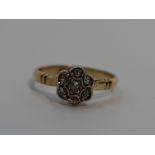 A lady's dress ring having an old cut diamond chip daisy cluster in a pave mount to shaped shoulders