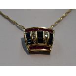 A yellow metal pendant stamped 14K set with three rows of sapphires interspersed by two rows of