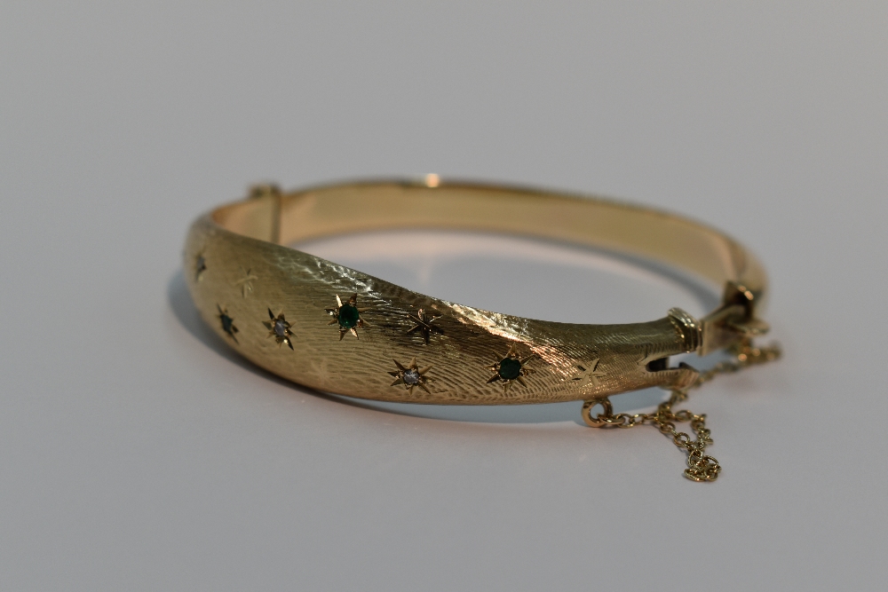 A 9ct gold hinged bangle having diamond and emerald chip decoration in star burst settings on - Image 2 of 2