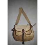 A wicker fishing creel with canvas and leather pouch and canvas top and strap.