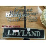 A quantity of vintage car badges and a metal Leyland sign.
