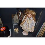 Two dolls with stands, a selection of necklaces and a mirrored photo frame.