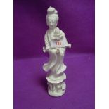 A Chinese figure or statuette in a Blanc De Chine style of Guanyin holding lotus