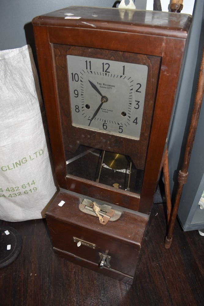 A vintage mahogany cased clocking-in machine, with square dial above the pendulum, mechanism and