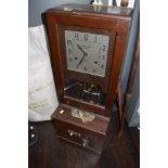 A vintage mahogany cased clocking-in machine, with square dial above the pendulum, mechanism and