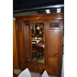 A Victorian mahogany double wardrobe having dentil cornice over mirrored centre panel flanked by