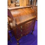 An early 20th Century part walnut/mahogany bureau having serpentine lower section, on ball and