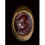 A large roman carnelian intaglio set in a gold ring. Bust of Athena.
