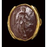 A postclassical carnelian intaglio set in a gold revival ring. Female figure with torch.