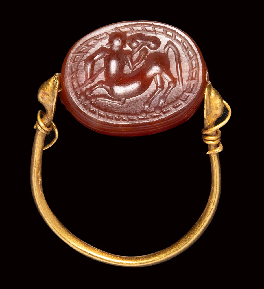 An etruscan carnelian scarab intaglio mounted on an ancient gold ring. Centaur.