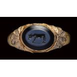 A roman nicolo intaglio set in an etruscan gold ring. Bull.