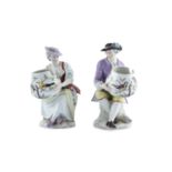 A GOOD PAIR OF BERLIN SEATED FIGURINES, 19th century, holding bowls, painted with birds, sceptre